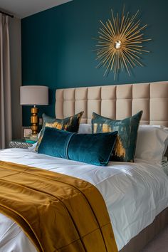 a bed with blue and gold pillows on top of it next to a wall mounted sunburst