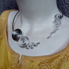 Sharm Open Metal Choker. Silver Necklace. Modern Style. Spiral Aluminum Silver Necklace. Statement Necklace.Bridal Jewelry. Bold Designe. Handmade. This spiral shape necklace is a statement piece, the perfect accessory to complete a stunning outfit look. Ideal for a casual fashion style. Materials:  - Aluminum wire (3 mm). The material I use to wrap aluminum wire, that means, is not heavy at all. Aluminum is lightweight and will never tarnish. I give it a slightly hammered texture and wrap the glass stone with it. SIZE: The necklace is 54 cm/ 21 inches in circumference  COLOR:  Silver, aluminum  wire Try to keep it away from water. Shipping time: This item is finished product and it will be sent immediately. Shipping time is 1 to 4 weeks (depends of your Custom office and Post office).  Th Aluminum Wire Jewelry, Choker Silver, Metal Choker, Edgy Jewelry, Wire Jewelry Tutorial, Spiral Shape, Silver Necklace Statement, Custom Office, Necklace Bridal