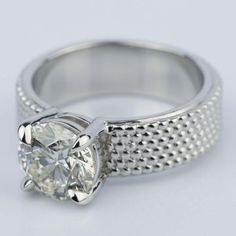 a white gold ring with an oval cut diamond in the center and dotted band around it