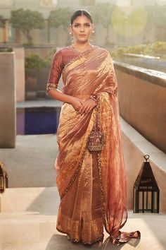 a woman in a brown sari standing on a ledge with her hand on her hip