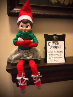 an elf doll sitting on top of a shelf next to a sign that says elf strike