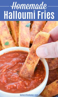 someone dipping some bread sticks into a bowl of homemade halloumi fres with tomato sauce