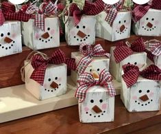 snowman gift boxes with red and white plaid bows on them sitting on a shelf