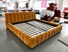 an orange bed frame sitting on top of a floor in a room filled with furniture