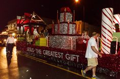 people are walking on the side of a float decorated with candy canes and presents