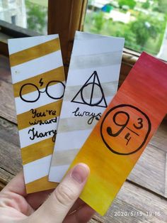 hand holding three harry potter bookmarks in front of a window