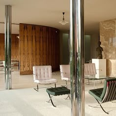 a living room filled with lots of furniture next to a tall glass table and chairs