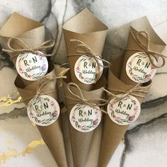 brown paper cones tied with twine and decorated with round stickers that read r n wedding