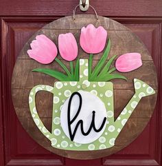 a wooden sign with pink flowers in a watering can and the letter h on it