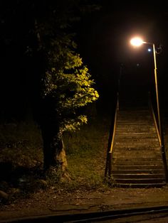 a set of stairs leading up to a light on top of it at night time