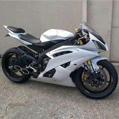 a white and black motorcycle parked in front of a garage door next to a building