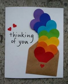 a card that says thinking of you with hearts in the box and paper on top