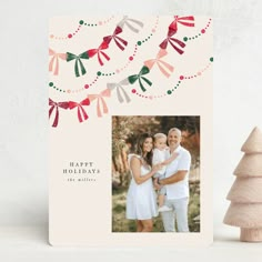 a christmas card with an image of two people and a tree on the left side