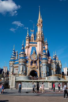 people are walking around in front of a castle with blue and pink decorations on it