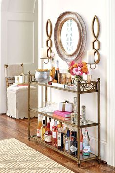 a bar cart with liquor bottles and candles on it in front of a wall mirror