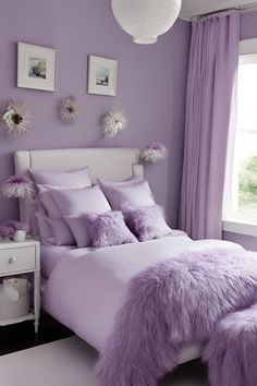 a bedroom with purple walls and white bedding, along with pictures on the wall