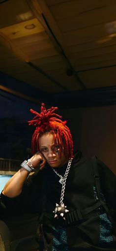 a man with red dreadlocks sitting in a chair