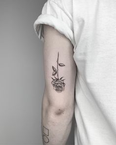 a black and white photo of a rose tattoo on the left upper half of the arm