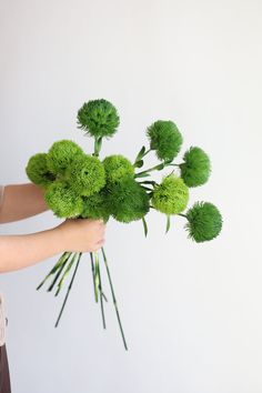 a woman is holding some green flowers in her hand and it looks like they are floating