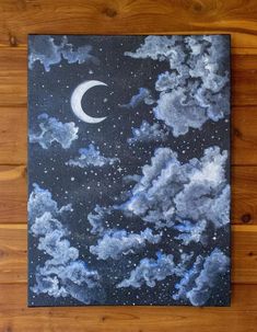 a painting on a wooden floor with clouds and a crescent moon in the night sky