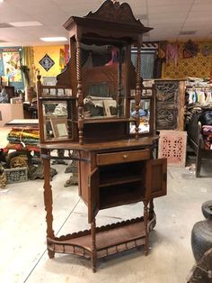 an old fashioned wooden cabinet with mirror on it's top and shelves below, in a store