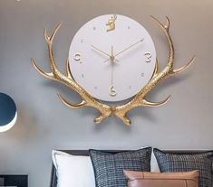 a white clock with gold deer antlers on it's face in a bedroom