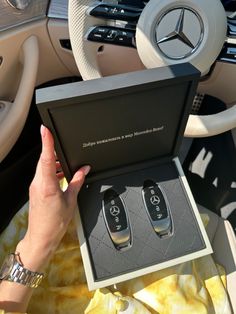 a woman is holding two mercedes remotes in her hand while sitting in the driver's seat of a car