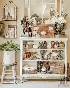 a white shelf filled with lots of pots and pans next to a wall mounted mirror