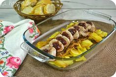 a glass casserole dish filled with meat and potatoes on a table next to bread