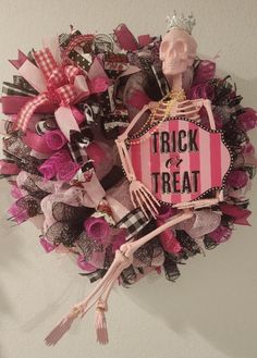 a wreath that has a skeleton holding a fork and trick or treat sign on it