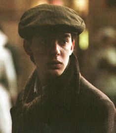 a young man wearing a brown hat and coat