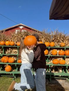 a man and woman standing next to each other in front of pumpkins