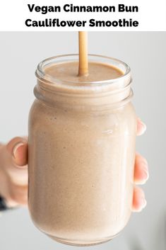 a person holding a mason jar filled with vegan cinnamon bun cauliflower smoothie