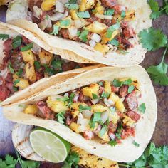 three tacos with meat, pineapple salsa and cilantro