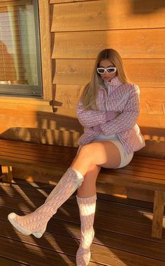 a woman sitting on a wooden bench wearing white socks and knee high socks with her legs crossed