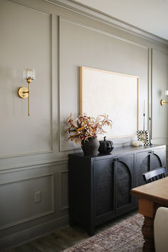 a black cabinet with a potted plant sitting on top of it next to a wooden table