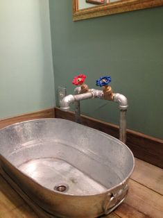 a large metal bowl sink sitting on top of a wooden floor next to a faucet