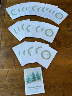 six cards with green ink on them sitting on a wooden table next to some paper