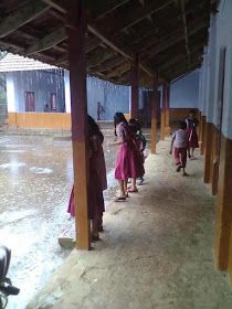 several children are walking down the sidewalk in front of a building that is flooded with water