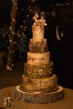 a three tiered wedding cake sitting on top of a wooden table with lights in the background