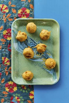 some food is on a green plate and next to a blue tablecloth with flowers