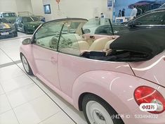 a pink convertible car parked in a showroom