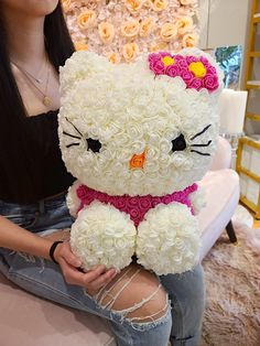 a woman sitting on a couch holding a hello kitty stuffed animal in her lap with roses all over it