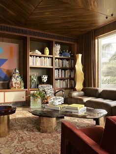 a living room filled with furniture and bookshelves next to a large painting on the wall