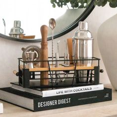 a stack of books sitting on top of a table next to a vase and mirror