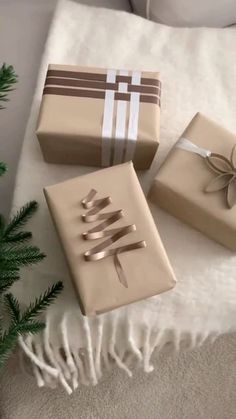 three wrapped presents sitting on top of a white blanket