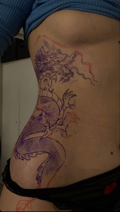 a woman's stomach with dragon tattoos on it