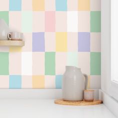 a white vase sitting on top of a counter next to a wall with colorful squares