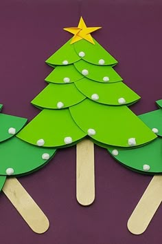 popsicle christmas tree cut out from green paper on purple background with yellow star and white dots