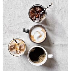 three different types of drinks on a white tablecloth, one with ice and the other with milk